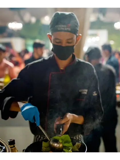 A chef at our "Dancing Wok" station, stir-frying fresh Asian greens and other ingredients with precision.