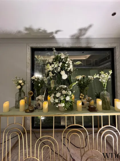 An elegant gold console table, decorated with an abundance of white flowers, candles, and a vintage-style telephone, creating a chic and timeless corner.