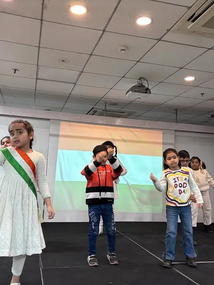 Students perform a patriotic dance on stage to celebrate Republic Day, expressing their love for the nation through coordinated movements.