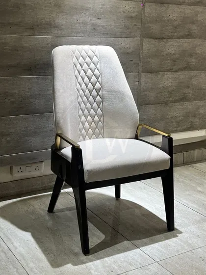 A high-back dining chair that exudes luxury. The quilted detailing on the backrest, combined with metal-capped arms and a sturdy wooden frame, creates a truly premium look.