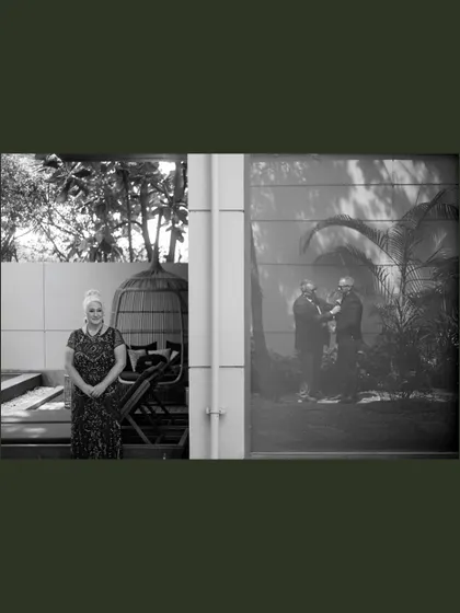 A mother watches on, her reflection captured alongside her son's happiness. This black and white shot speaks volumes about family love that travels across the globe to witness a new beginning.