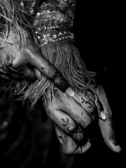 A detailed black and white shot of a couple's hands, showing the bride's intricate mehndi.