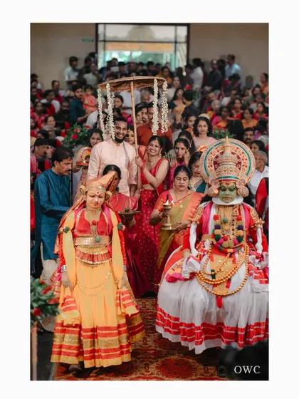 The grand entrance of the groom under a traditional umbrella, accompanied by Kathakali dancers.