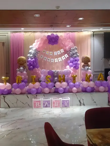 A wide shot of the naming ceremony venue, showing the decorated stage in the context of the banquet hall.