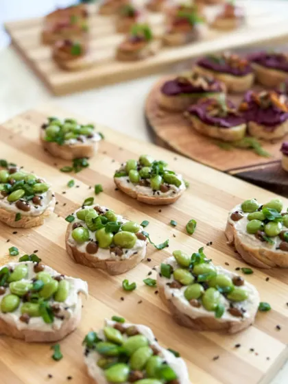 A close-up of our edamame tartines, topped with sesame seeds and fresh herbs. A perfect bite-sized snack for any occasion.