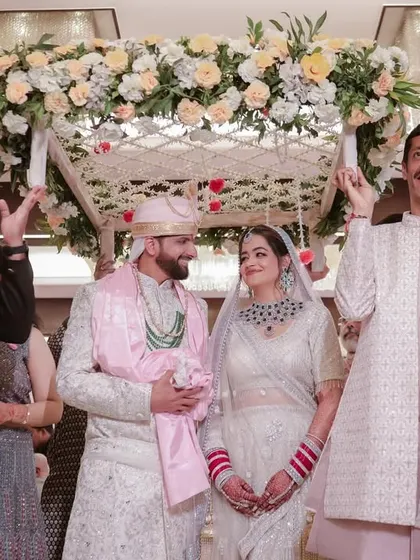 The couple under the 'phoolon ki chadar' as they enter. We capture the family's involvement and the beautiful traditions of an Indian wedding.