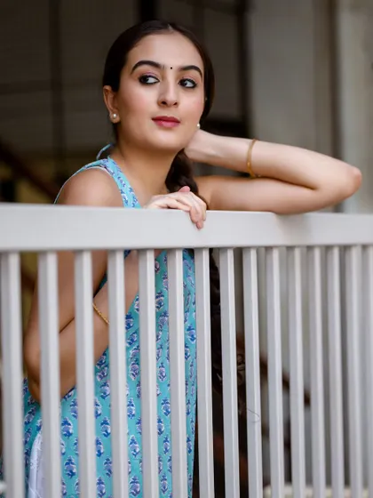 A thoughtful pose, looking out from behind the railing. The soft outdoor light is perfect for this kind of gentle, narrative portrait.