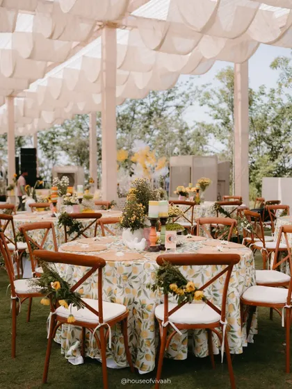 Dining tables at the Haldi, draped in lemon-print tablecloths and surrounded by wooden cross-back chairs adorned with small floral bouquets.