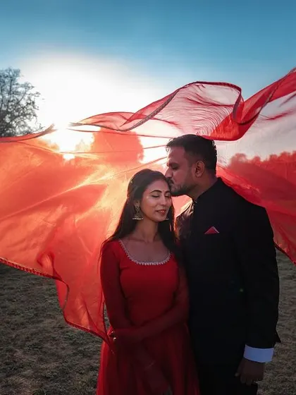 We incorporate elements like flowing fabrics to add movement and a touch of Bollywood-inspired drama to your pre-wedding photos. This shot uses a vibrant red cloth to create a dynamic and romantic frame.