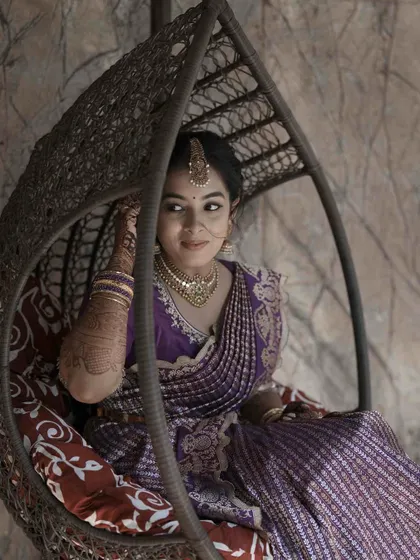 A candid shot of the bride in a swing chair, her expression full of grace. The makeup is soft and enhances her natural features.