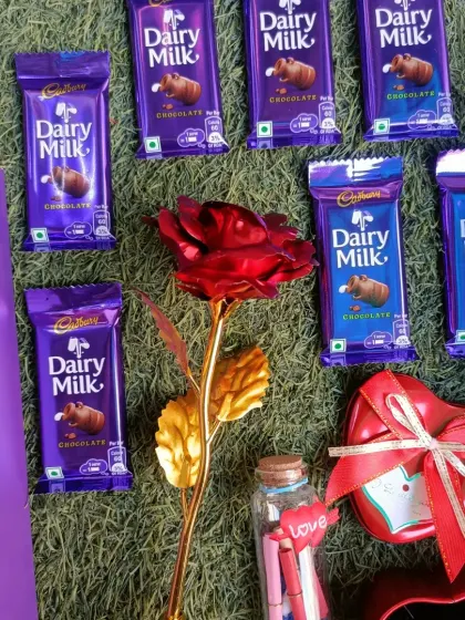 Our Valentine's Day combo for her includes everything she loves: Dairy Milk chocolates, a golden rose, a message bottle, and a heart-shaped necklace.