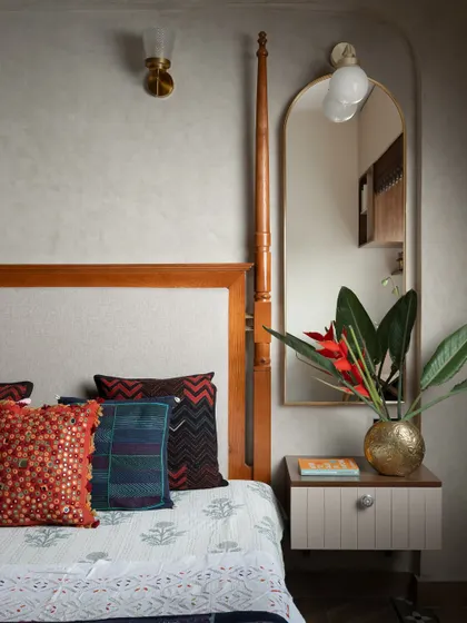 Every detail in this bedroom is a gentle nudge towards comfort. The classic four-poster bed is adorned with hand-embroidered cushions, and a floating nightstand with an arched mirror adds a touch of modern elegance.