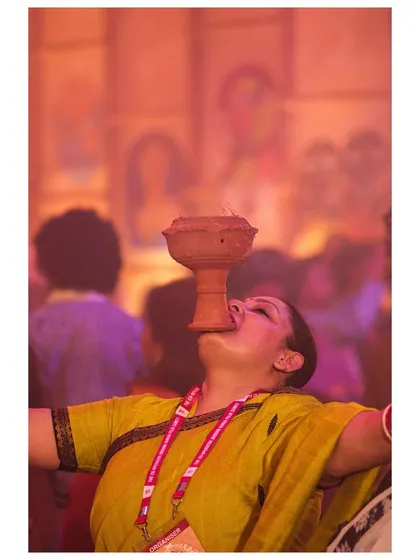 Lost in devotion, a woman balances the smoking dhunuchi in her mouth, a feat of faith and balance during the Durga Puja celebrations.