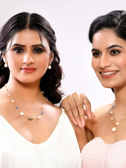 Two models display a collection of pearl and gemstone necklaces, demonstrating how different pieces can be styled together.