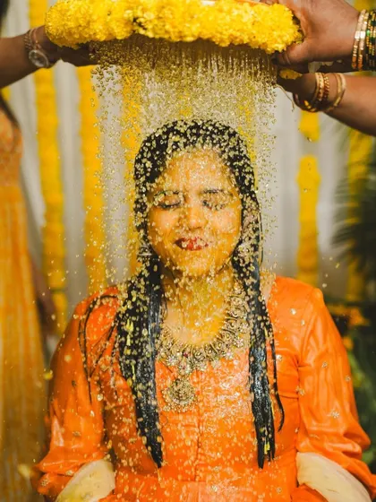 A serene moment during the Haldi ceremony, as the bride is showered with flowers. The yellow marigold decor creates a warm and auspicious ambiance.