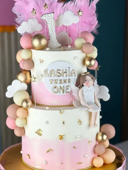Turning one never looked so sweet. This angelic first birthday cake features soft pink and white ombre, fluffy clouds, and a sparkling number one topper for a heavenly celebration.