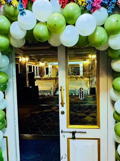 A welcoming entrance for a baby shower, decorated with a lush balloon arch in shades of green and white. We also incorporate floral elements to add a touch of freshness to the decor.