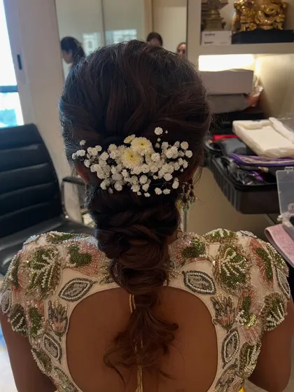A soft and romantic braided hairstyle, decorated with baby's breath and small daisies. This look is perfect for a Mehendi or Sangeet event.