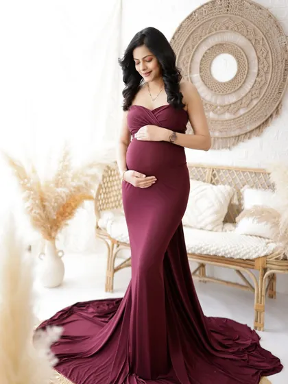 A duplicate of image 317, this elegant portrait in a rich burgundy gown highlights the mom-to-be's beautiful silhouette in a boho-chic setting.