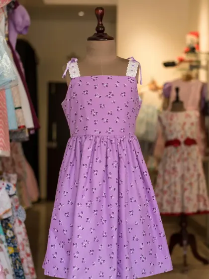 A full view of the lovely lavender floral dress, showing its simple A-line cut and charming tie-straps.