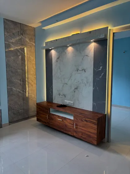 Here is a look at a modern living room featuring a floating TV console we built. The design combines a rich wood grain finish with a sophisticated marble-look backdrop. We integrated both ambient backlighting and focused spotlights to create a dramatic effect and highlight the textures.