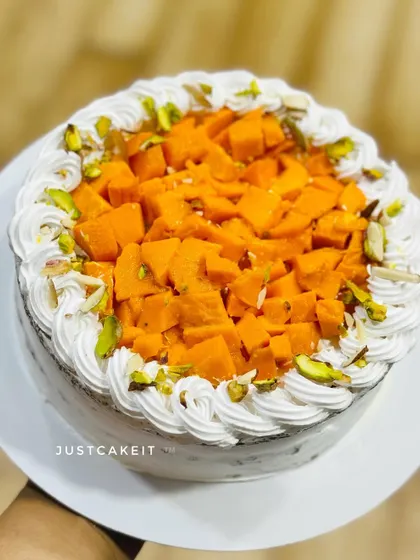 A close-up of the fresh mango cake, showing the generous topping of sweet, diced mangoes and pistachio slivers.