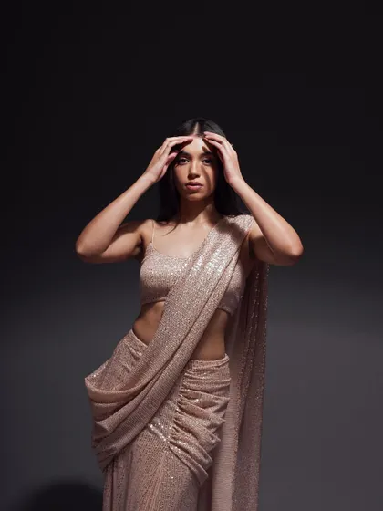 A powerful portrait focusing on the upper body. The model's pose and the dramatic studio lighting highlight the texture of the sequined fabric and create a high-fashion mood.