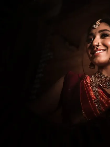 A low-key portrait capturing the bride's happy smile. The light is focused just on her, making her radiant expression the center of this intimate and joyful shot.