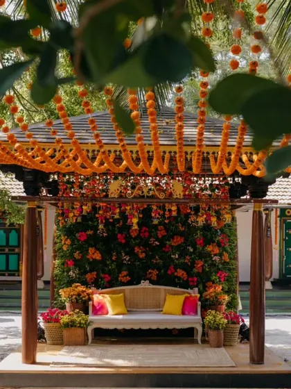 A traditional Haldi setup at The Tamarind Tree, with a canopy of marigold strings creating a vibrant orange ceiling over the courtyard.