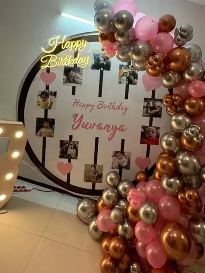 A personalized 3rd birthday with a photo display backdrop and a balloon arch in pink and metallic colors.