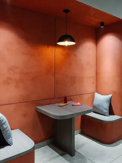 A close-up of the terracotta-colored breakout nook, showing the textured walls and simple, functional furniture.