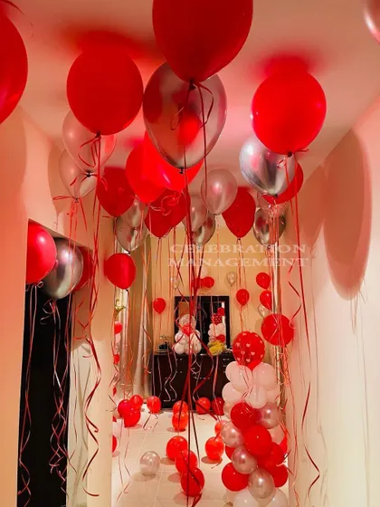 I filled this entire hallway and room with red and silver balloons to create an immersive celebration experience. It builds anticipation as you walk through the balloon-filled corridor to the main surprise.