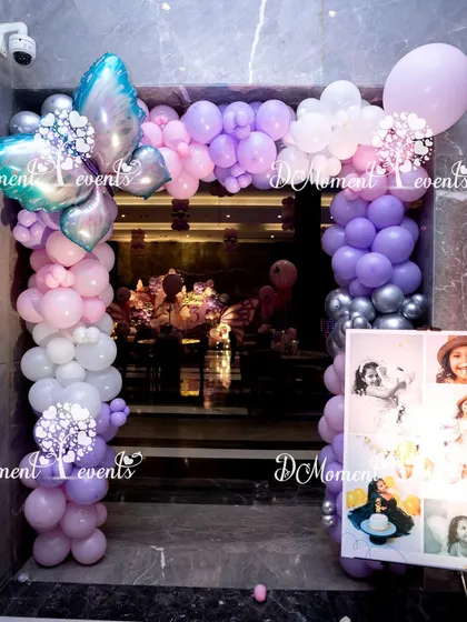 A balloon arch entrance for a butterfly-themed 3rd birthday, complete with a photo collage of the birthday girl.