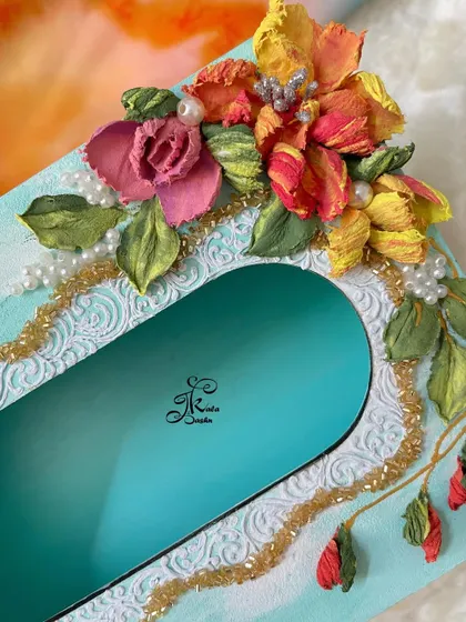A detail shot of the colorful tissue box, focusing on the mix of flowers and the delicate pearl and gold bead strings.