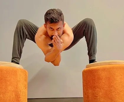 A floating Malasana, or garland pose, between two props. This requires significant core and leg strength to hold the body suspended.