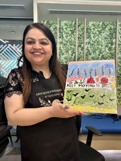 A participant from the Statkraft workshop proudly displays her finished piece with the powerful reminder to "Keep Moving."