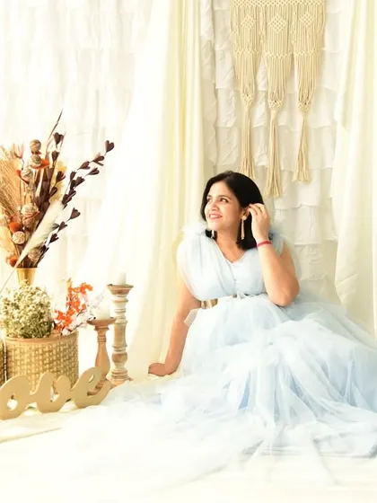 A serene solo portrait of the mom-to-be in a flowing light blue gown. She is seated in our bright, boho-inspired set, creating a calm and peaceful image.
