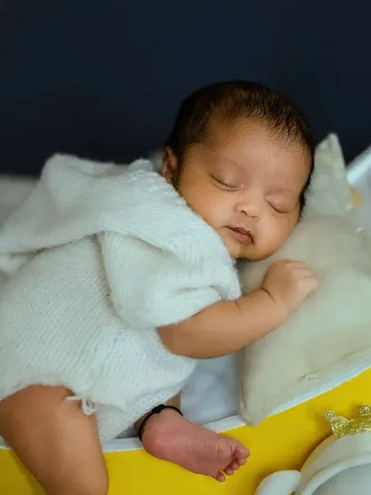The soft focus on the background stars keeps the attention on the sleeping newborn, creating a beautiful and artistic baby portrait.