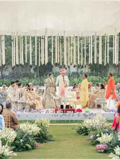 A wide shot of a beautiful outdoor wedding ceremony, where the bride's complete look includes her stunning mehndi.