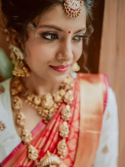 A close-up portrait capturing the bride's serene expression and the intricate details of her temple jewelry.