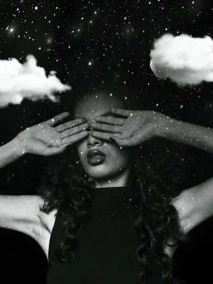 A creative and conceptual portrait. This black and white image uses surreal elements like clouds and stars to create a dreamy, artistic mood, with the makeup kept subtle to complement the theme.