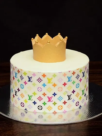 A touch of luxury with this Louis Vuitton inspired cake. The sides are wrapped in an edible print of the colorful LV monogram, and it's topped with a simple, elegant gold fondant crown.