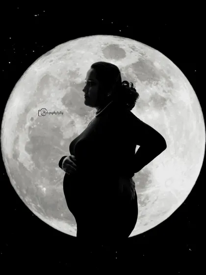 A beautiful silhouette of a mother-to-be against a full moon backdrop, creating a powerful and artistic image.