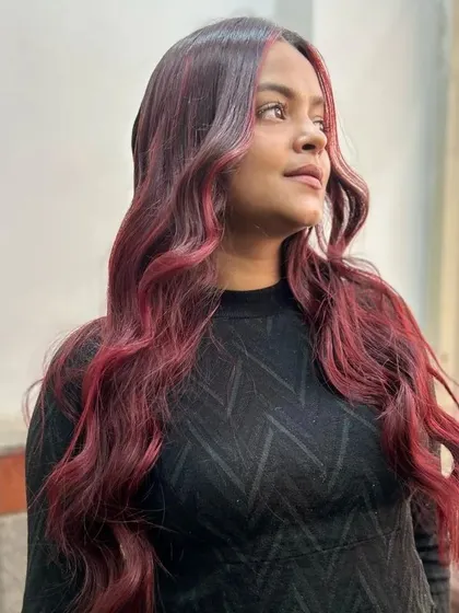 A profile view of the beautiful red and burgundy color melt, showing how the face-framing pieces brighten her complexion.