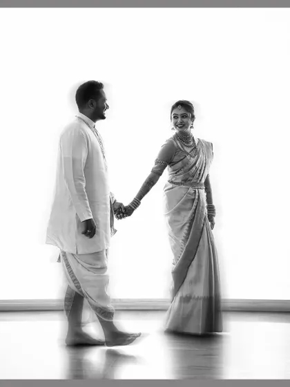 A timeless black and white portrait of a couple holding hands, their traditional wedding attire creating a beautiful silhouette.