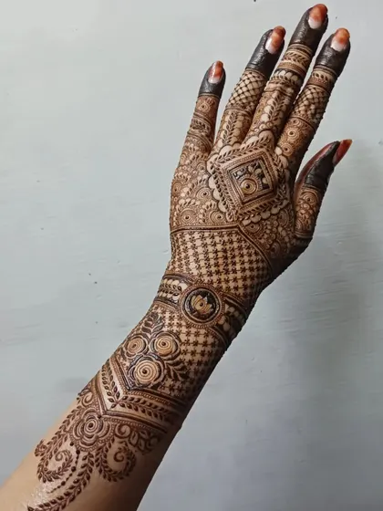 A complete view of an intricate back-hand design that extends up the arm. The pattern flows from a central geometric element, using a mix of grids and traditional motifs for a stunning effect.