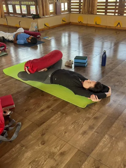 A student finds complete surrender in a supported Savasana, using a bolster to enhance the restorative effect.