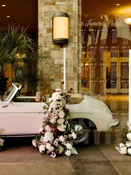 A creative seating chart display using a vintage car and a large acrylic sign. This is a fantastic example of how day-of stationery can be integrated into the overall event design.