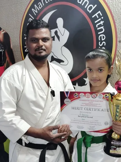 This young green belt student proudly displays her second-place trophy from the karate championship.