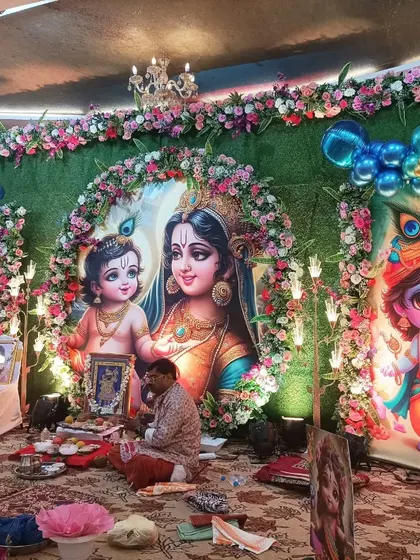 This was a grand baby shower with a divine Yashoda and Krishna theme. The main stage features large, beautifully illustrated backdrops framed with flowers and balloons, creating a sacred space for the ceremony.
